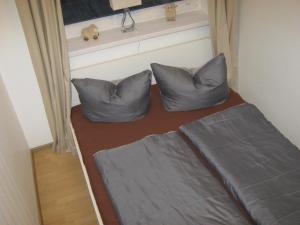 1 cama con 2 almohadas en una habitación pequeña en Fewo 91 WHG B 9 in Burhave, en Burhave