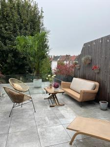 a patio with chairs and a couch and a table at Petit cocon lillois:Cheminée & jardin in Lille