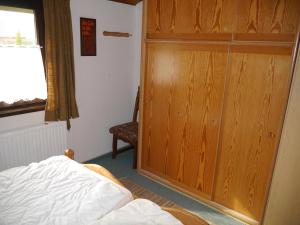 a bedroom with a bed and a wooden closet at Bungalow M 43 in Burhave in Burhave