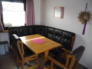 a living room with a table and a leather couch at Bungalow M 07 in Burhave in Burhave