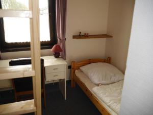 a small bedroom with a bed and a desk and a window at Bungalow M 07 in Burhave in Burhave