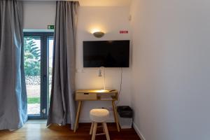 a room with a desk and a television on a wall at Penedo Escape Sea Suites in Colares