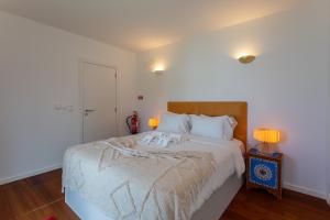 a bedroom with a large white bed with two lamps at Penedo Escape Sea Suites in Colares