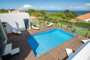 a swimming pool on a wooden deck next to a house at Penedo Escape Sea Suites in Colares