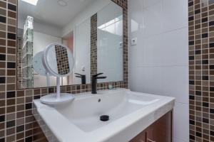 a bathroom with a white sink and a mirror at Penedo Escape Sea Suites in Colares