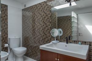 a bathroom with a sink and a toilet and a mirror at Penedo Escape Sea Suites in Colares
