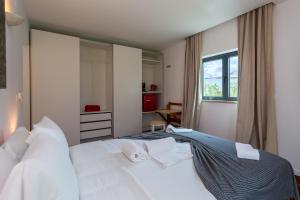 a bedroom with a bed with two towels on it at Penedo Escape Sea Suites in Colares