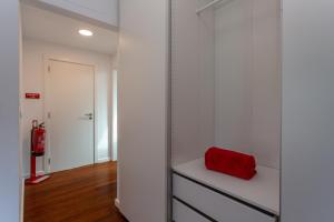 a room with a white closet with a red object on a shelf at Penedo Escape Sea Suites in Colares