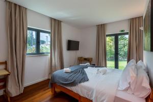 a bedroom with a bed with white sheets and windows at Penedo Escape Sea Suites in Colares +37 photos