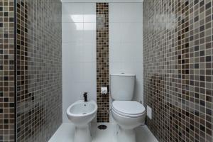 a bathroom with a toilet and a sink at Penedo Escape Sea Suites in Colares
