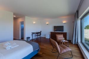 a bedroom with a bed and a table and chairs at Penedo Escape Sea Suites in Colares
