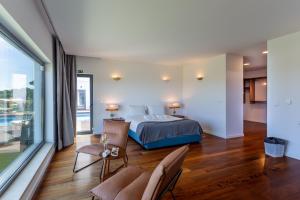 a bedroom with a bed and a large window at Penedo Escape Sea Suites in Colares