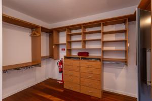 a walk in closet with wooden shelves and cabinets at Penedo Escape Sea Suites in Colares