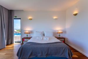 a bedroom with a large bed with two night stands at Penedo Escape Sea Suites in Colares
