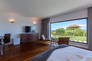 a hotel room with a bed and a large window at Penedo Escape Sea Suites in Colares