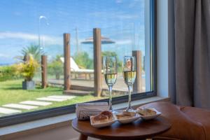 two glasses of wine on a table next to a window at Penedo Escape Sea Suites in Colares