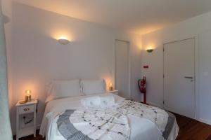 a white bedroom with a bed with two candles on it at Penedo Escape Sea Suites in Colares