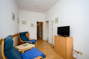 a living room with two blue chairs and a television at Strandnelke in Graal-Müritz