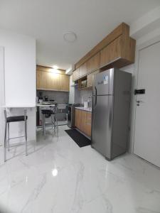 une cuisine avec un réfrigérateur en acier inoxydable et des armoires en bois dans l'établissement Canário - Apartamento perto do Allianz Park e Metrô, à São Paulo