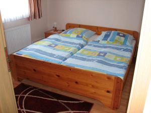 a bed with a wooden frame with blue and yellow sheets at Hering in Grossenbrode