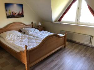 - une chambre dotée d'un grand lit avec des draps blancs et une fenêtre dans l'établissement To Hus, Reihenhaus 7, à Kellenhusen