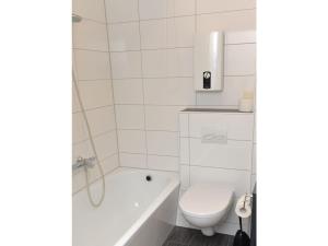 een witte badkamer met toilet en ligbad bij Fewo 91 WHG A 12 in Burhave in Burhave +6 foto's