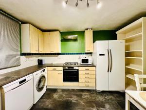 a kitchen with white appliances and green walls at Opulent Marriott in London