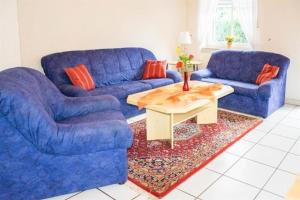 ein Wohnzimmer mit 2 blauen Sofas und einem Couchtisch in der Unterkunft Margret HA22 in Sögel