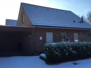 ein rotes Backsteinhaus mit Schnee auf dem Boden in der Unterkunft Margret HA22 in Sögel