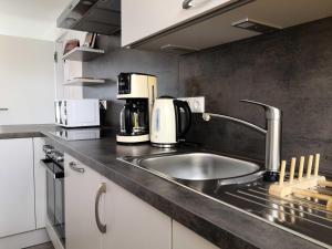 eine Küche mit einer Spüle und einer Kaffeemaschine auf der Theke in der Unterkunft FeWo Prora - MeerSonneWind in Binz