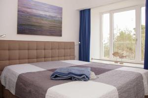 ein Schlafzimmer mit einem Bett mit einer Decke und einem Fenster in der Unterkunft FeWo Prora - MeerSonneWind in Binz + 7 Fotos