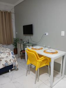 a white table and two yellow chairs in a room at Studio Bastos Residence in Recife