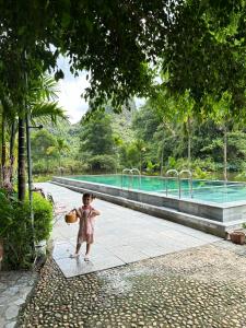 un niño pequeño parado frente a una piscina en Hello Valley Bungalow, en Vũ Lâm