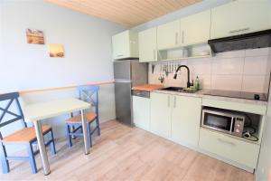 eine Küche mit weißen Schränken und einem Tisch und einer Spüle in der Unterkunft Bungalow Janik in Dahme