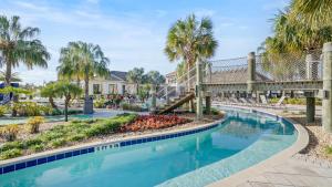 a swimming pool with a bridge and palm trees at Fabulous Villas 5 minutes away from Disney! in Kissimmee