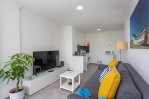un salon avec un canapé bleu et une télévision dans l'établissement BeGuest Beachfront Apartment Caparica Lisbon, à Costa da Caparica