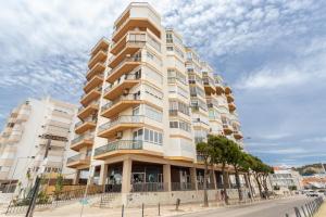 un grand immeuble situé dans une rue avec des arbres devant dans l'établissement BeGuest Beachfront Apartment Caparica Lisbon, à Costa da Caparica