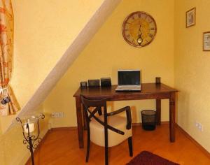 ブレーメンにあるDeluxe Apartments Bremen Typ Dのデスク(ノートパソコン付)、壁掛け時計が備わります。