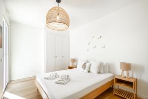 um quarto branco com uma cama e uma luz pendente em BeGuest Only Good Vibes - Cabanas em Tavira