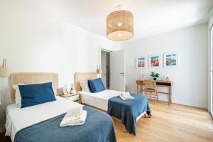 um quarto com 2 camas com lençóis azuis e uma mesa em BeGuest Only Good Vibes - Cabanas em Tavira