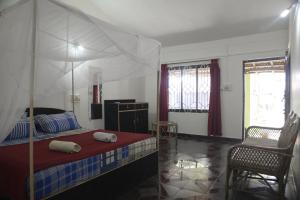 een slaapkamer met een hemelbed en een stoel bij Om Shanti Beach Stay Patnem in Patnem