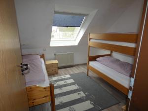 une petite chambre avec deux lits superposés et une fenêtre dans l'établissement To Hus, Reihenhaus 6, à Kellenhusen