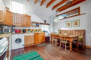 eine Küche mit Holztisch und eine Küche mit Waschmaschine in der Unterkunft Park View Cottages - The Granary in Boarhills
