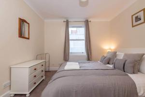 a bedroom with a bed with a dresser and a window at Achaniar Cottage in St. Andrews