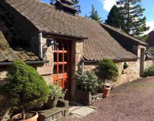 ein altes Cottage aus Stein mit einer roten Tür in der Unterkunft Park View Cottages - The Granary in Boarhills