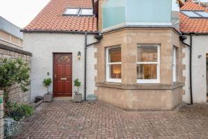 a house with a red door and a brick driveway at Achaniar Cottage in St. Andrews