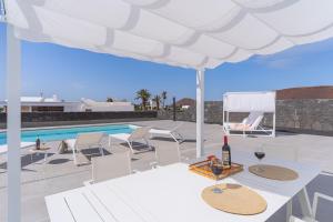 a table with a glass of wine under a white umbrella at Vv Villa Secretos de Yaiza 2 by HH - private pool in Yaiza