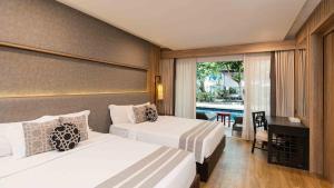 ein Hotelzimmer mit 2 Betten und einem Balkon in der Unterkunft Phuket Graceland Resort and Spa in Patong Beach