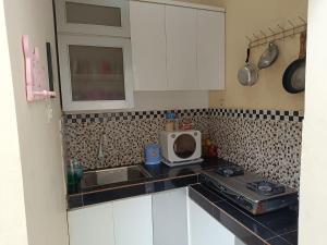 a kitchen with white cabinets and a stove and a microwave at Than's Homestay Wonosobo in Ngasinan