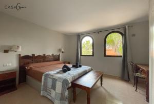 sypialnia z łóżkiem ze stołem i 2 oknami w obiekcie Rentalfue Tamarindo 1 casa Grace w Corralejo